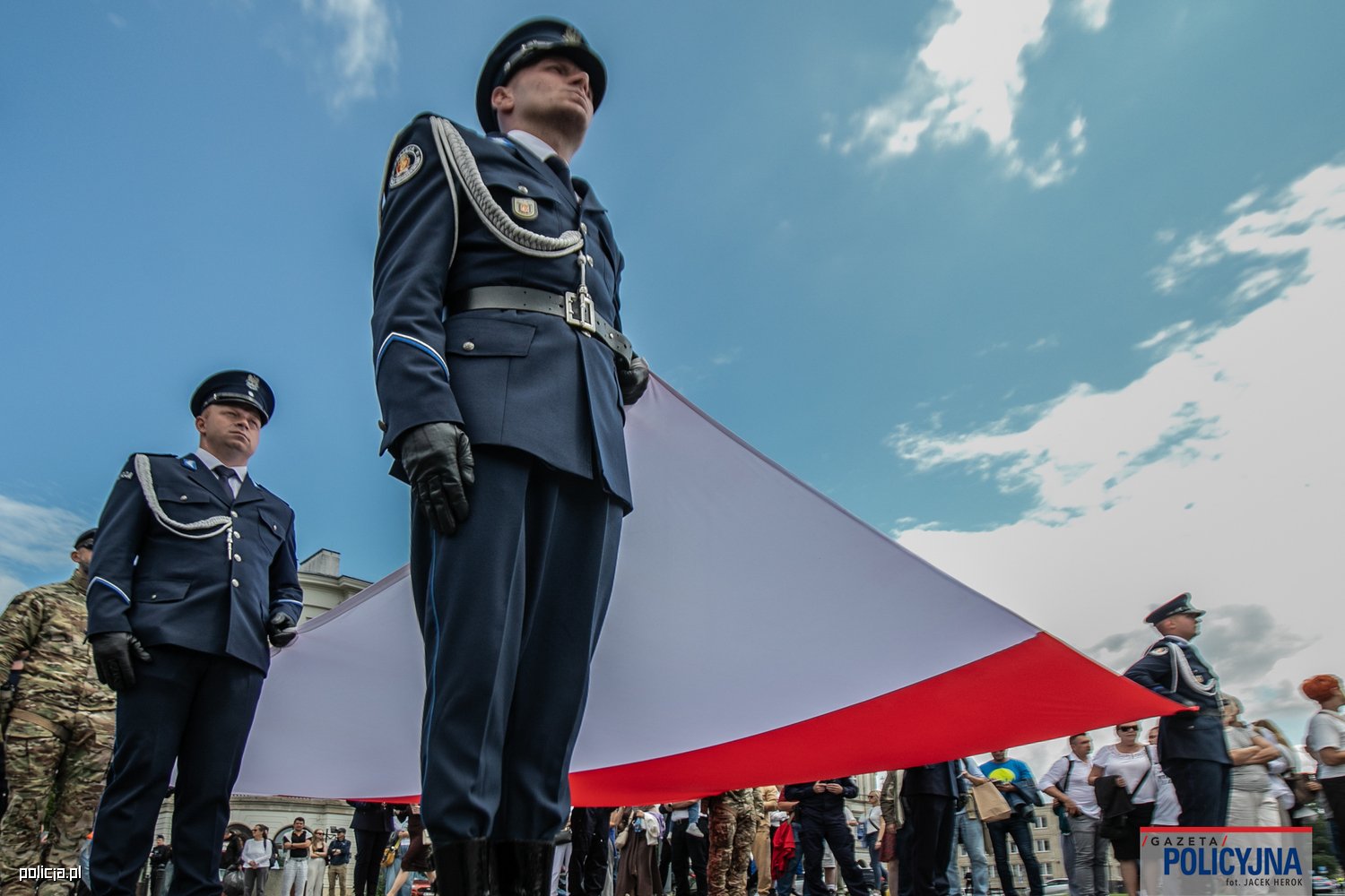 Policjanci trzymają flagę na Placu Marszałka Józefa Piłsudskiego.